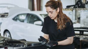Female technician fixing car parts in a garage