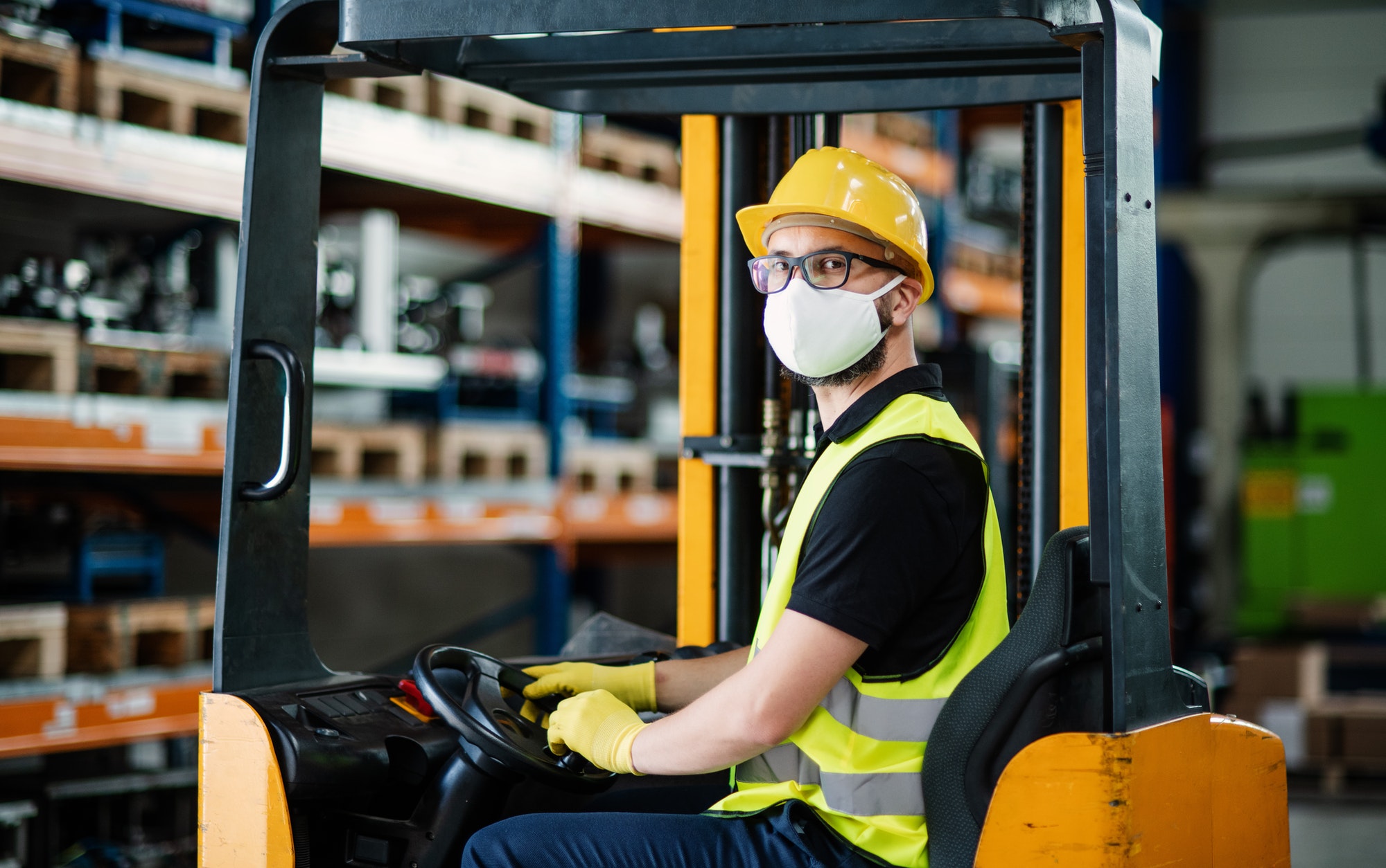 Man worker forklift driver with protective mask working in industrial factory or warehouse