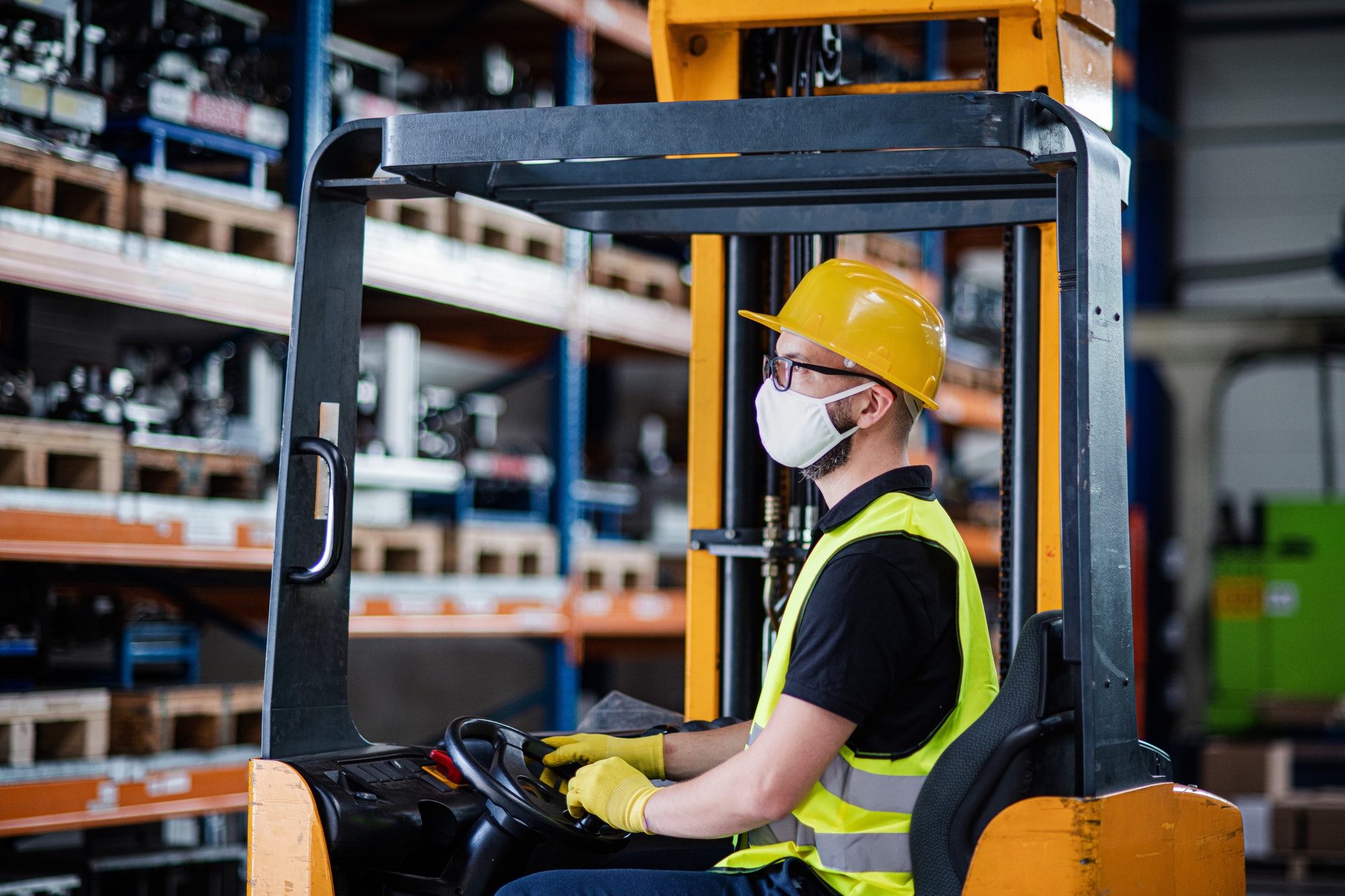 Man worker forklift driver with protective mask working in industrial factory or warehouse
