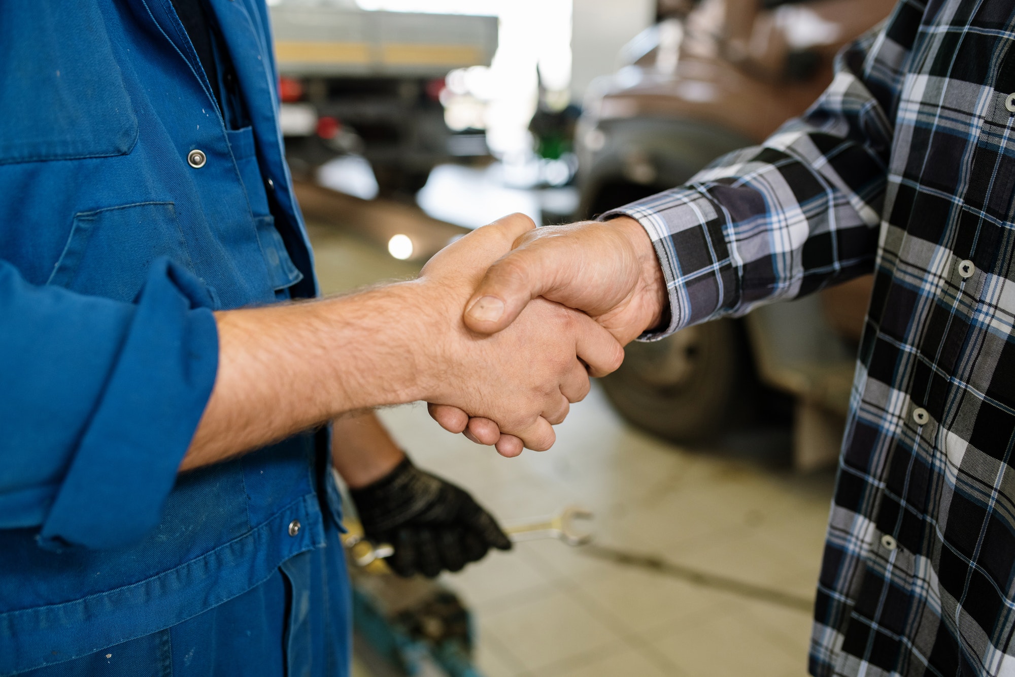 Young client of repair service and technician greeting one another by handshake